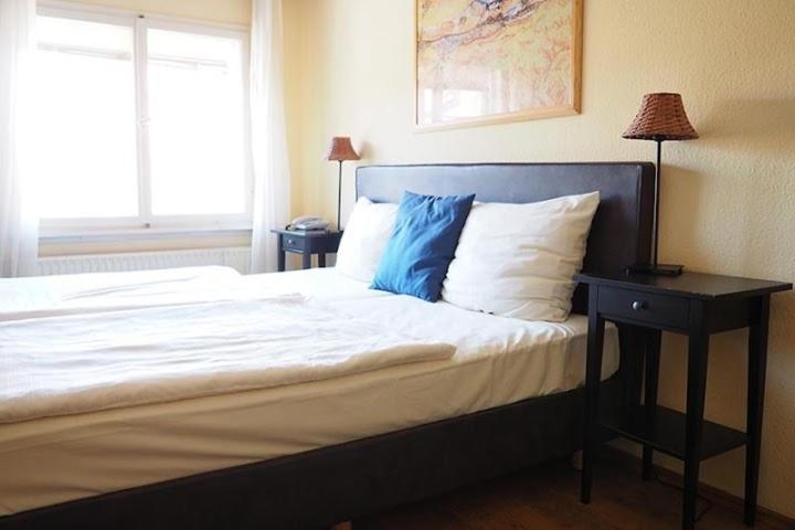 a bedroom with a large bed with a nightstand and a window at Hotel Restaurant Iris in Bad Segeberg