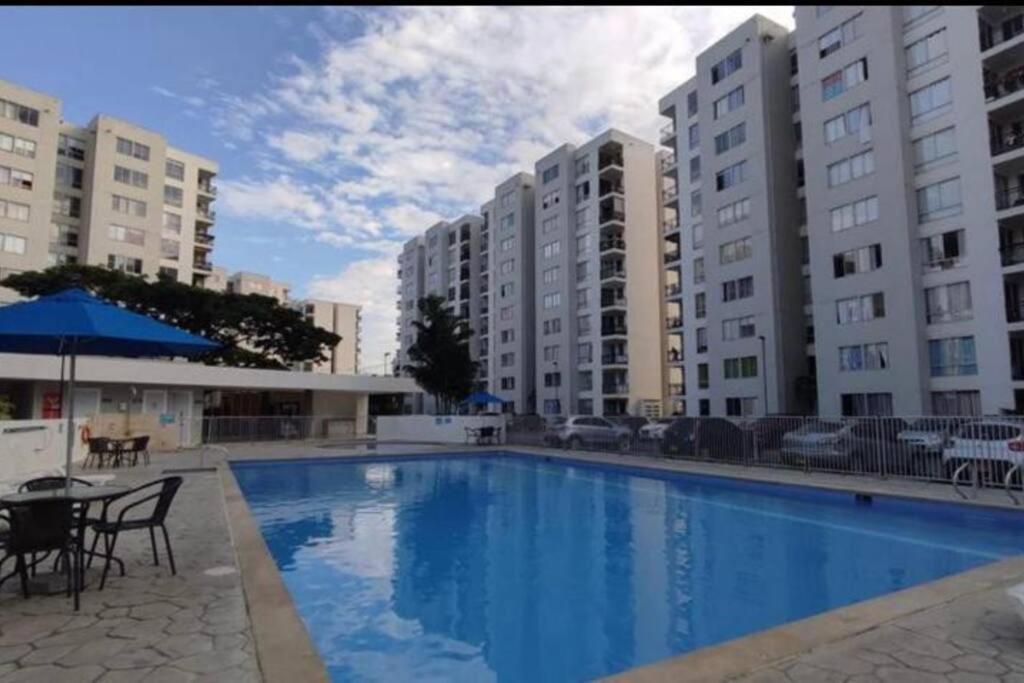 een zwembad met tafels, stoelen en gebouwen bij hermoso apartamento con piscina in Yumbo