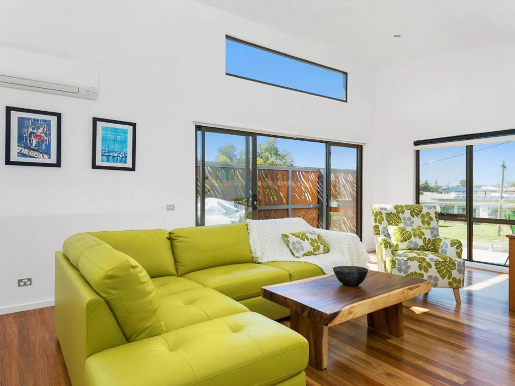 sala de estar con sofá verde y mesa en Soho Beach House - Apollo Bay, en Apollo Bay