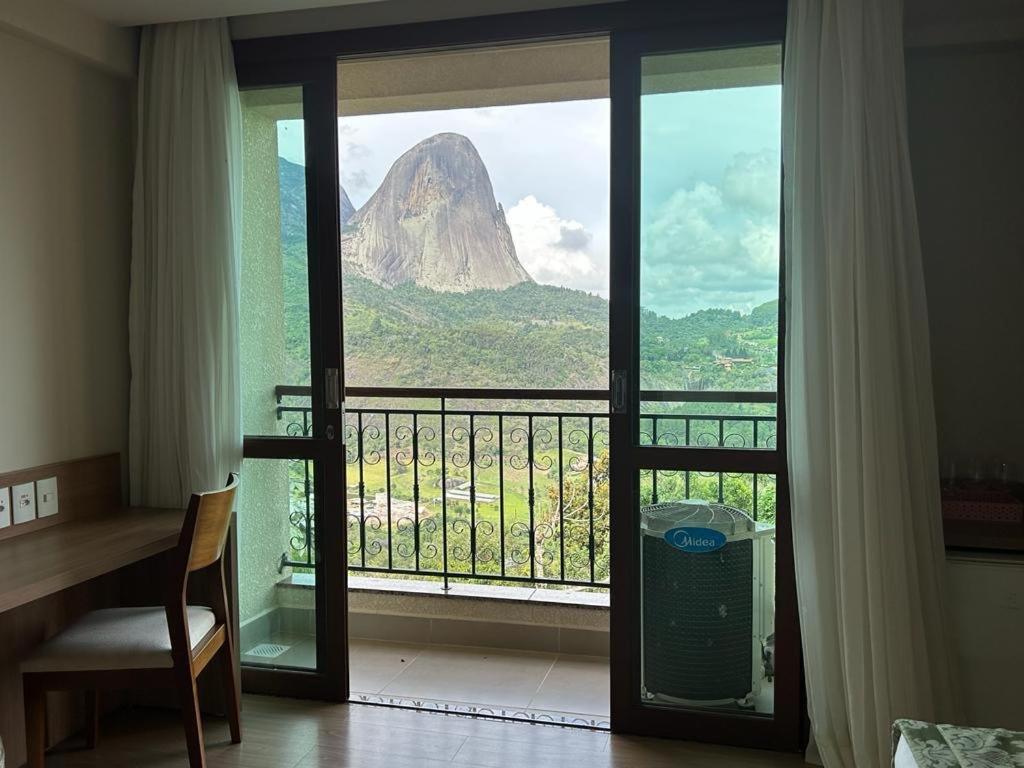 a room with a window with a view of a mountain at Suíte Vista Azul - Frente para Pedra Azul in Pedra Azul