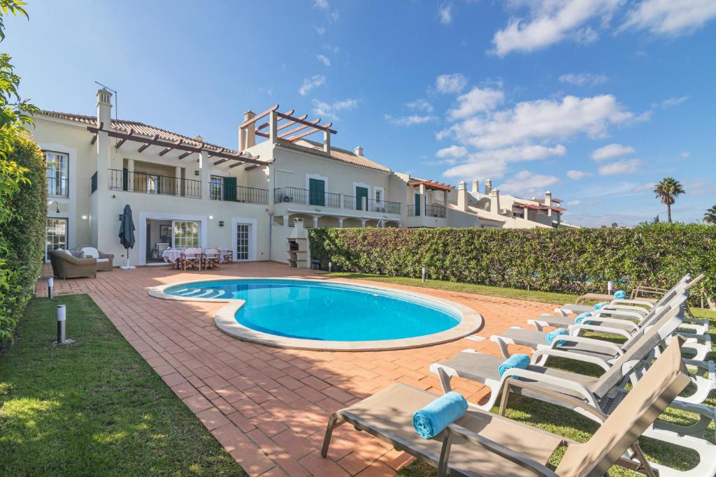 a villa with a swimming pool and lounge chairs at Vilamoura - VILLA VINTE in Vilamoura