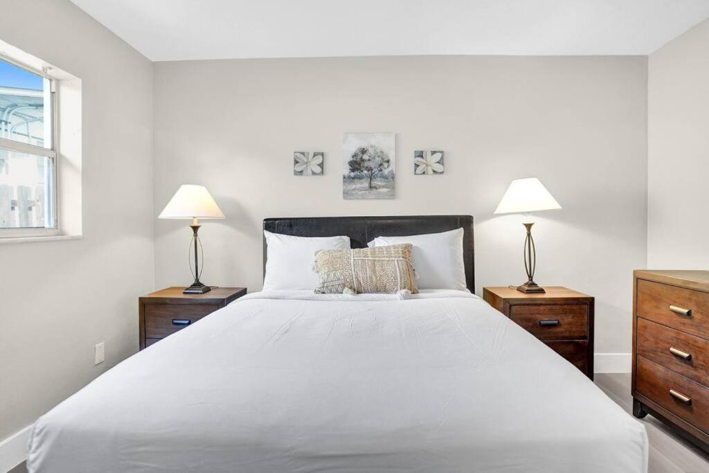 a white bedroom with a large bed and two lamps at Pionciana Getaway 1BR Apartment Near FLL Airport in Fort Lauderdale