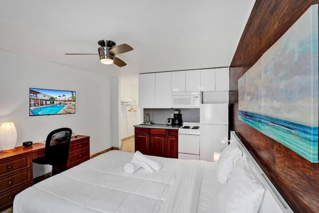 a bedroom with a white bed and a kitchen at Waves Beach Town Studio Apartment in Pompano Beach