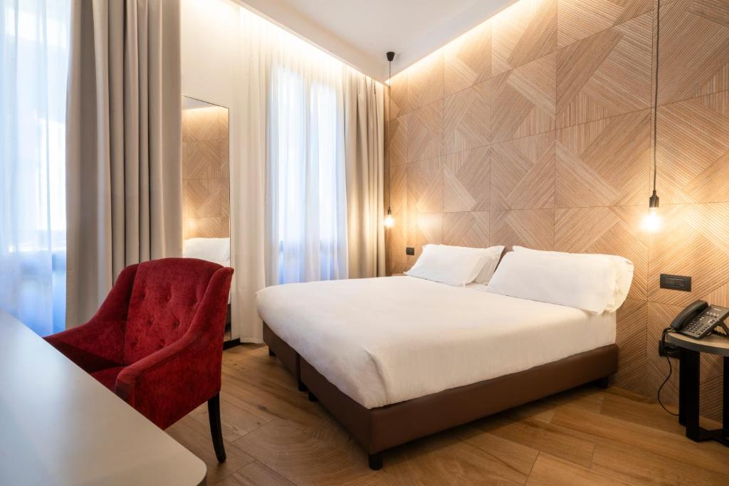 een hotelkamer met een bed en een stoel bij London Hotel in Milaan