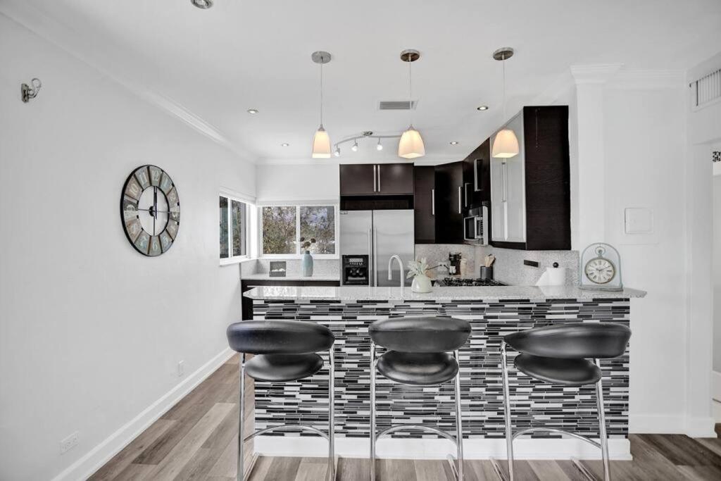 a kitchen with a bar with stools and a clock at Beach Isles Modern 1BR Apartment in Fort Lauderdale in Fort Lauderdale