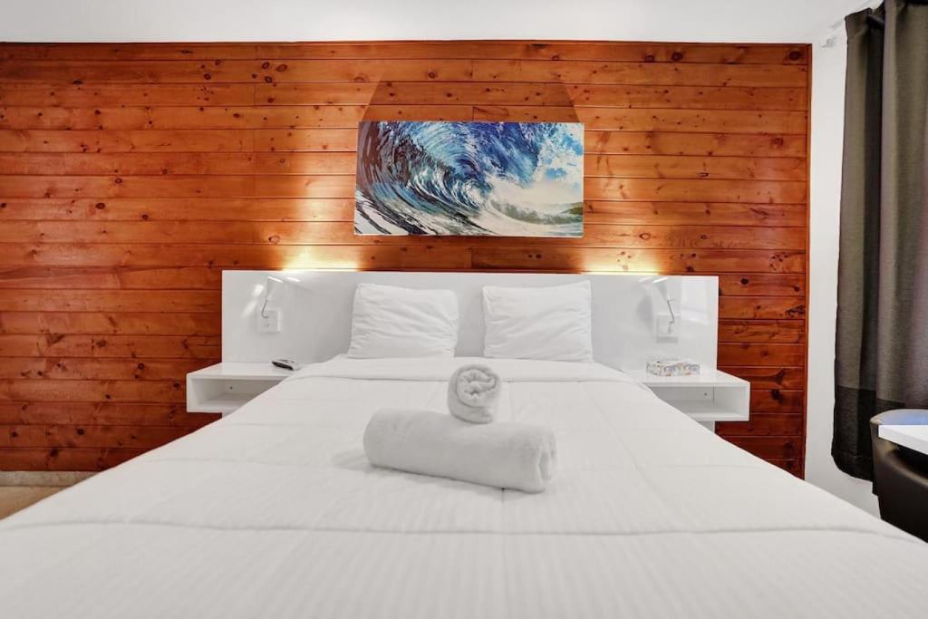 ein Schlafzimmer mit einem weißen Bett und einem Gemälde an der Wand in der Unterkunft Waves Beach Town Cozy Studio Apartment in Pompano Beach