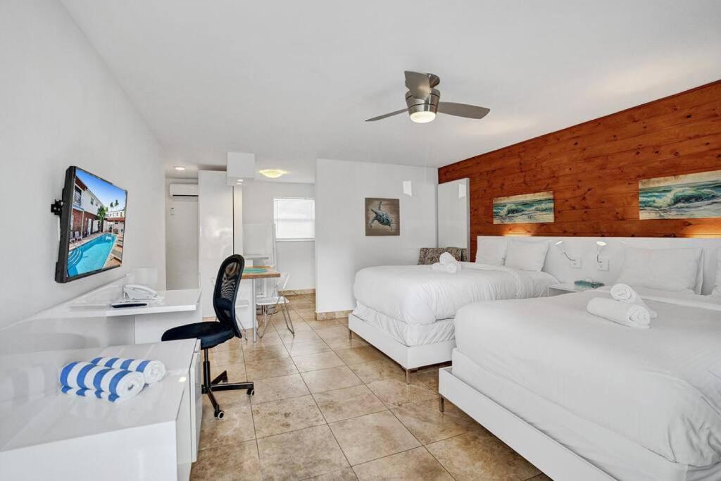 a bedroom with two beds and a desk and a tv at Waves Beach Town Cozy Studio Apartment in Pompano Beach
