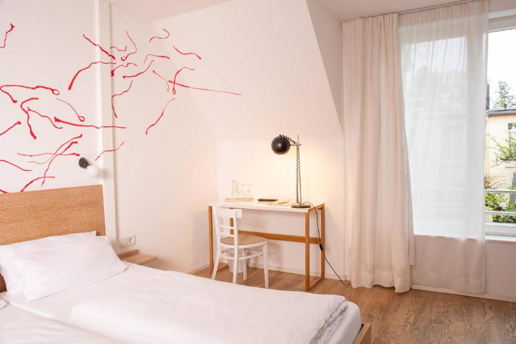 a bedroom with a bed and a desk and a window at Hotel Tafelfreuden in Oldenburg