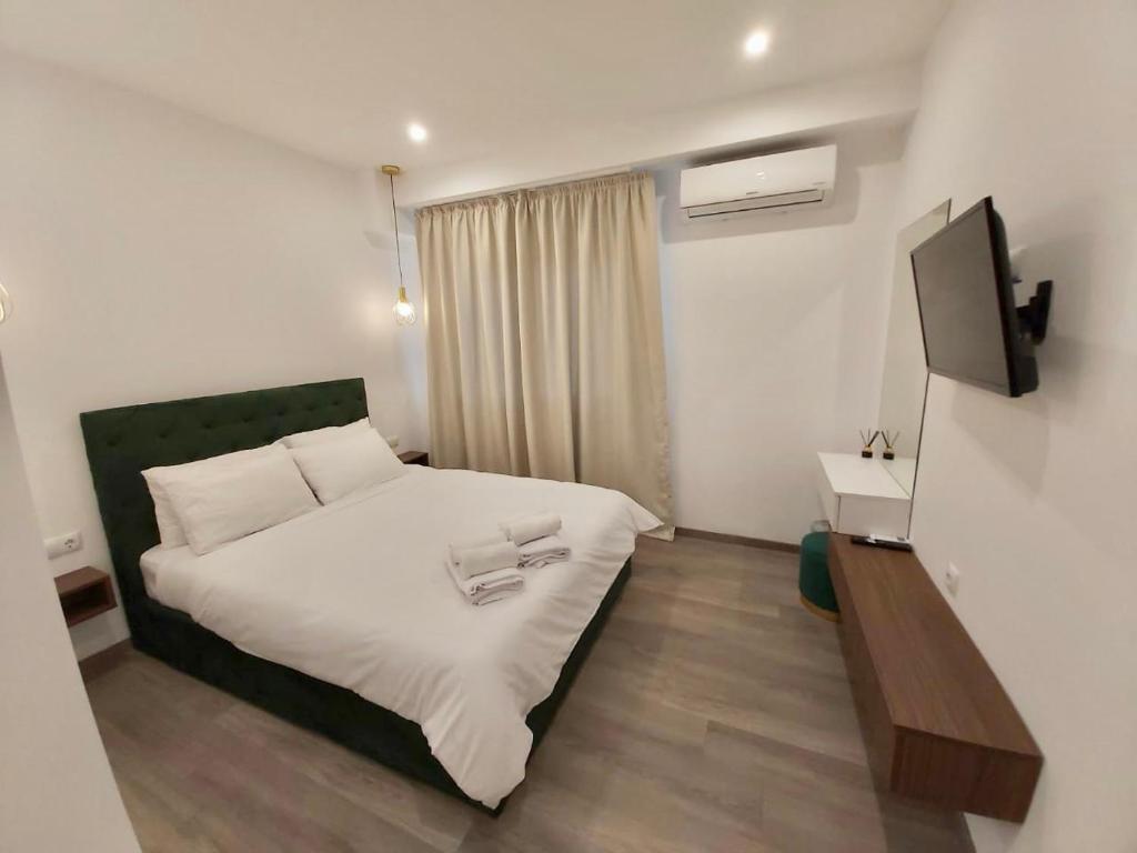 Schlafzimmer mit einem weißen Bett und einem TV in der Unterkunft Real City Suites Syntagma in Athen