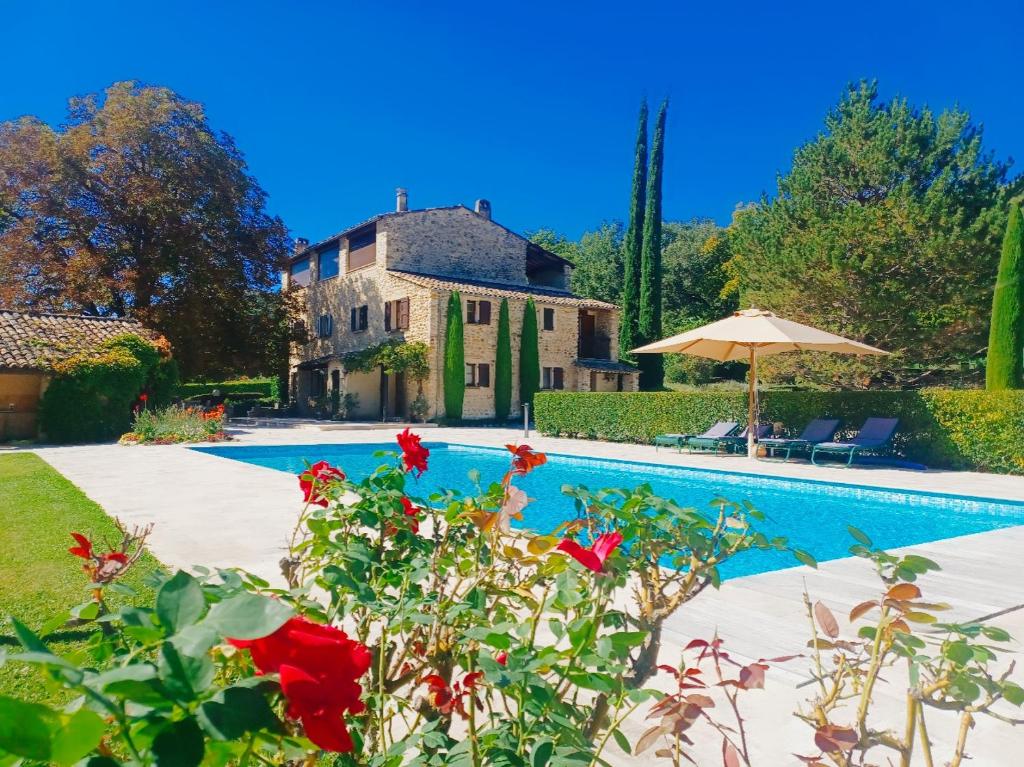 una casa y una piscina con rosas rojas en Le Moulin de l'Asse Chambre d'Hôtes, en Bras-dʼAsse