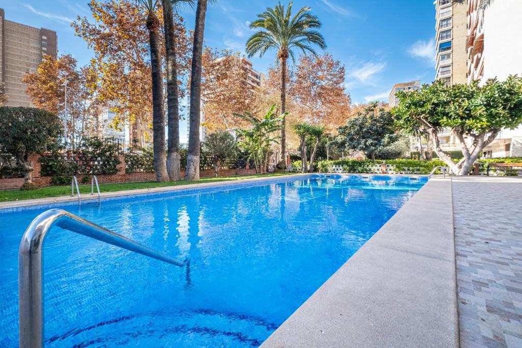 a swimming pool with blue water and palm trees at Edimar 2-3 Apartment Levante Beach in Benidorm