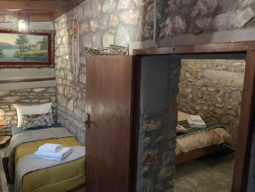 a bedroom with two beds and a stone wall at Αυθεντικό πετρινο στην Ναύπακτο in Nafpaktos