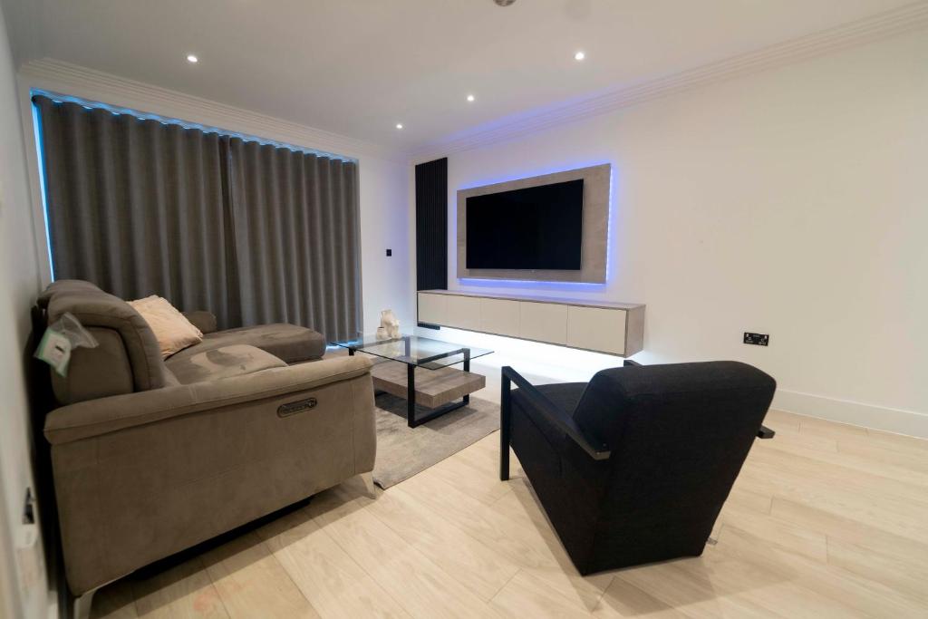 uma sala de estar com um sofá e uma televisão de ecrã plano em Luxury, Modern & Cosy 1 Bedroom Prestige London Apartment em Londres