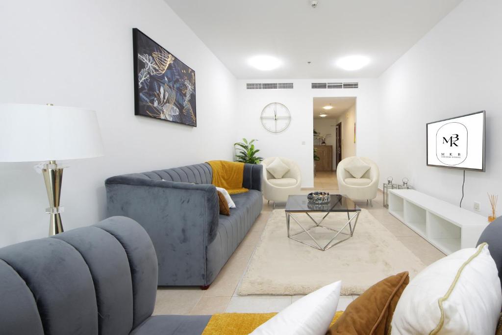 sala de estar con sofá azul y mesa en Sunny Seaside 2 Bedroom Apartment, Dubai Marina en Dubái