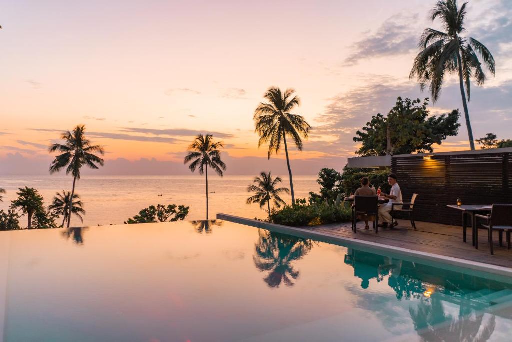 una pareja sentada en una mesa junto a una piscina en Nest Sense Resort, en Ko Chang