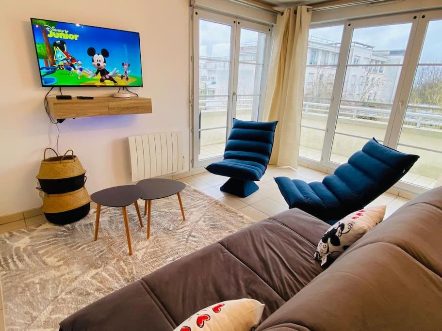 un salon avec un canapé et une télévision à écran plat dans l'établissement Mickey's House Disneyland Paris, à Montévrain