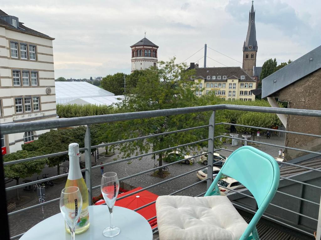 - un balcon avec une table et deux verres de vin dans l'établissement AVI City Burgplatz Apartments, à Düsseldorf