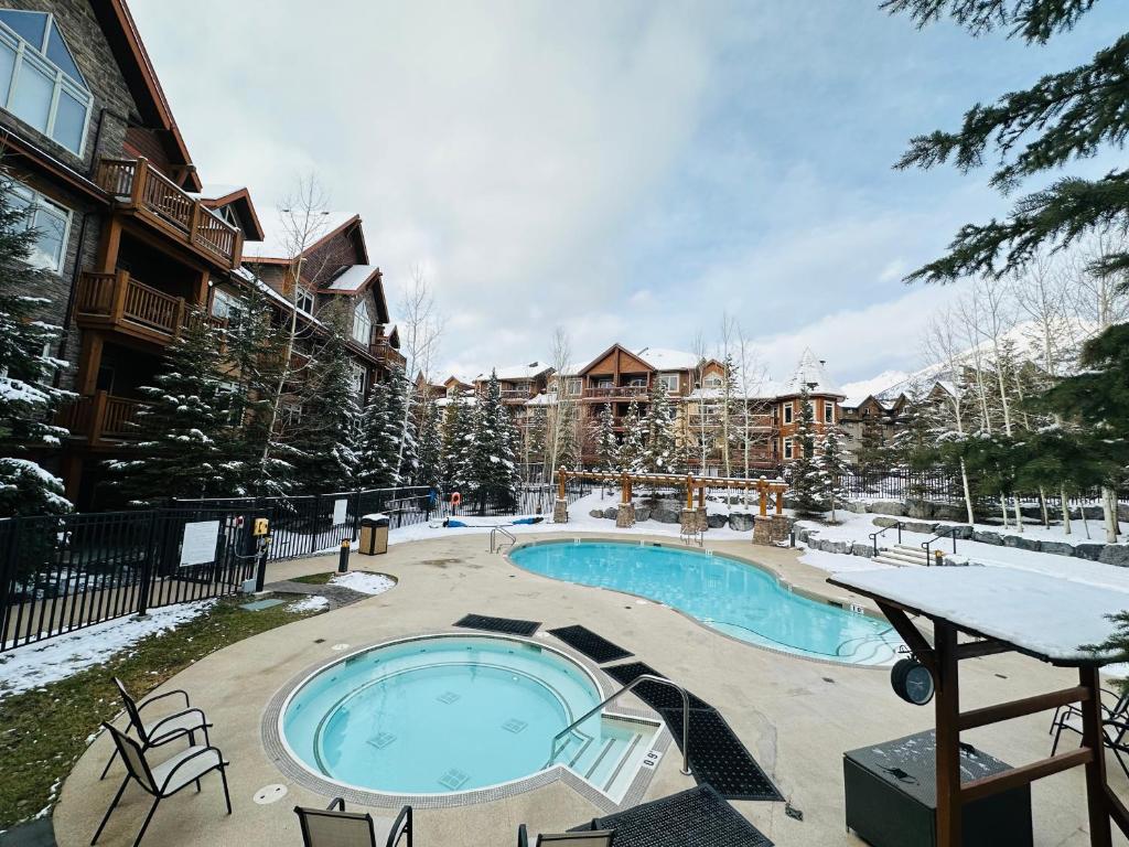 a swimming pool in front of a apartment building with snow at Canmore Mountain Retreat - Heated Pool & Hot-tub in Canmore