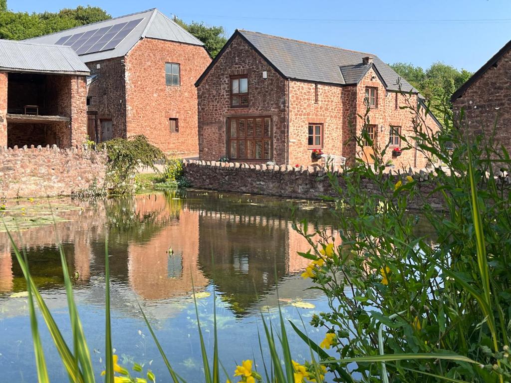 a group of brick buildings next to a body of water at Mill Pond Cottage in Taunton