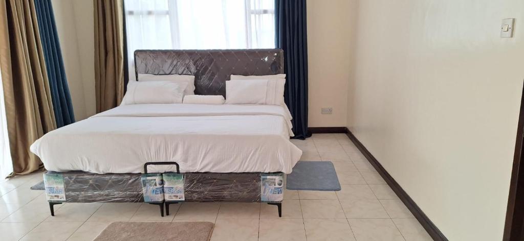 1 dormitorio con 1 cama grande y cabecero de metal en Genesis Executive mlimani en Kisumu