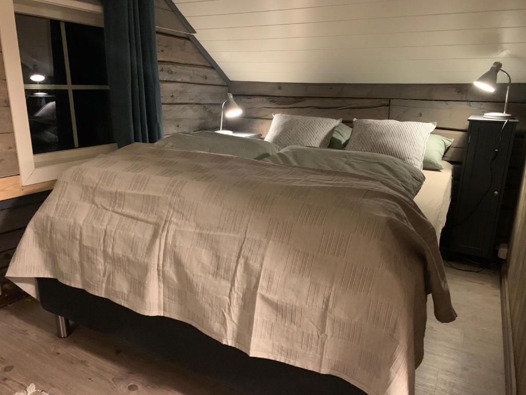 a bedroom with a large bed with two lamps on it at Lyngen Biarnes- Nordreisa in Hamnnes