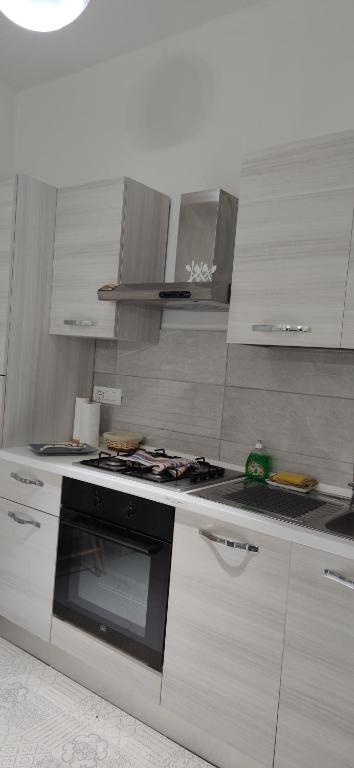 a kitchen with a stove top oven and white cabinets at Casa Gimaga in Pozzuoli