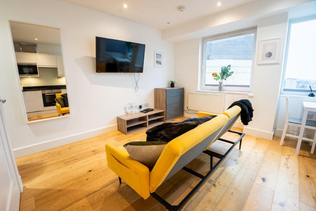 a living room with a yellow couch and a tv at Homely Entire Apartment - Long Stay, Contractors - Central Location in Croydon