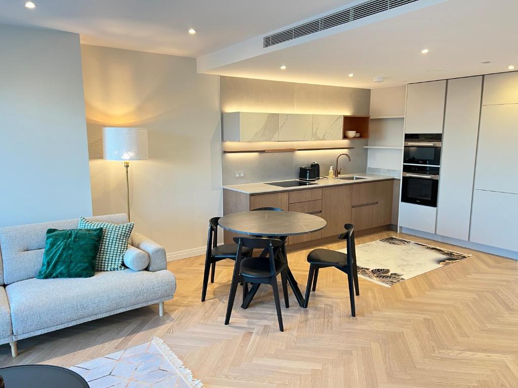 a kitchen and living room with a table and a couch at 2 Bedroom Modern Family Flat-Apartment Fulham London in London