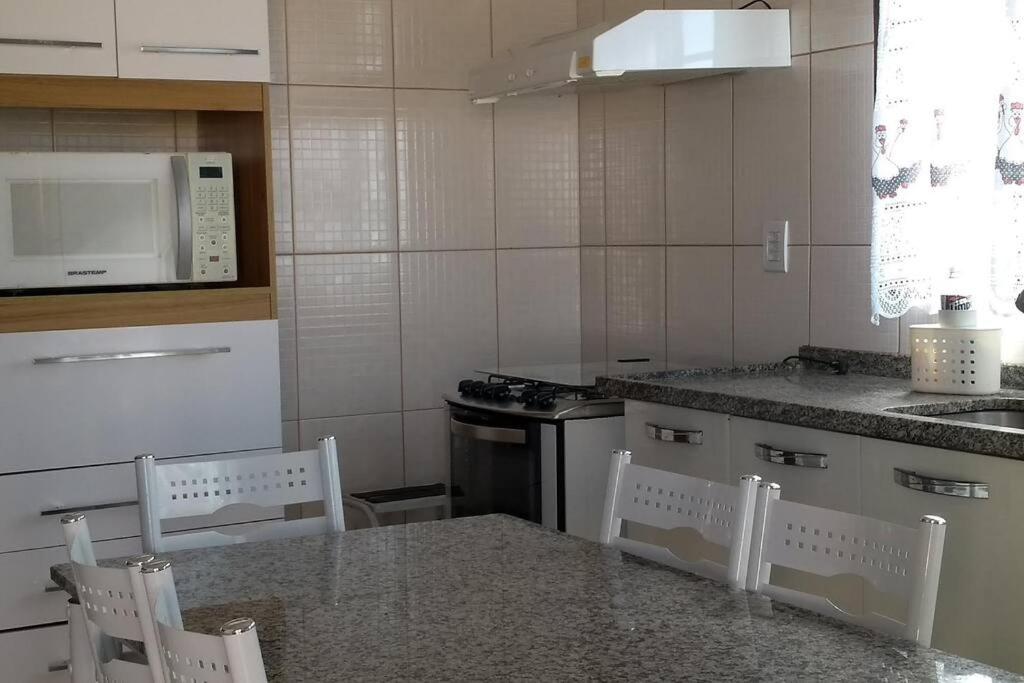 een keuken met een tafel en stoelen en een magnetron bij casa privativa para família com ar condicionado in Olímpia