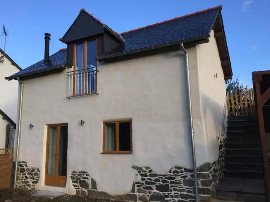 une maison blanche avec un toit noir et des escaliers dans l'établissement Charmant gîte rural en Bretagne, à Rouillac