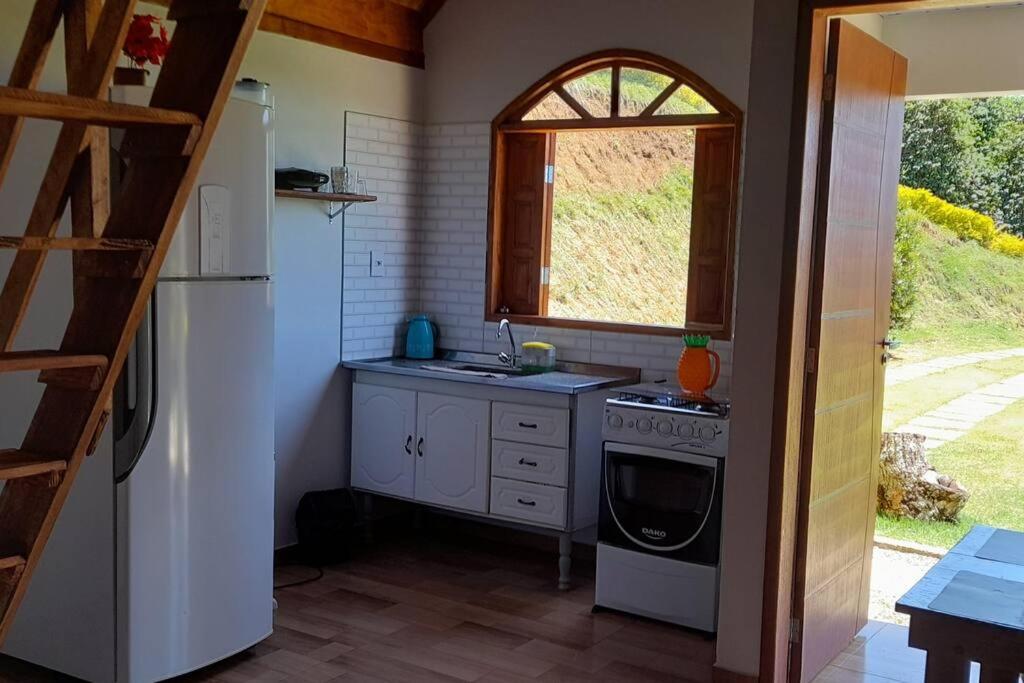 eine Küche mit einer Spüle, einem Herd und einem Fenster in der Unterkunft chale 2 canto das montanhas in Caparaó Velho
