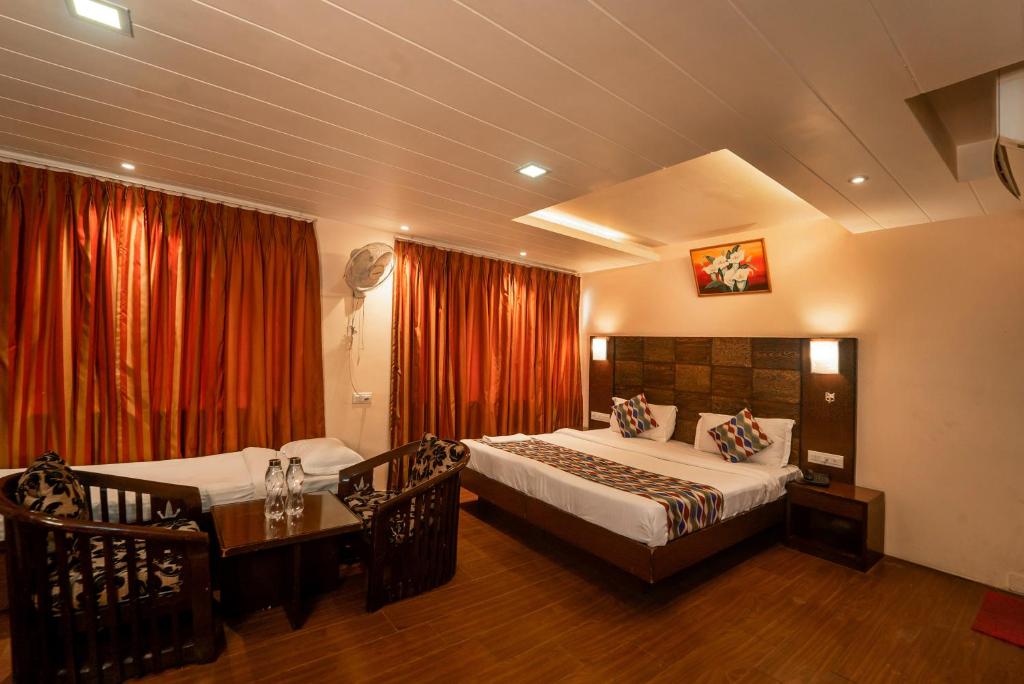 a bedroom with two beds and a table and a window at Vatika Inn Hotel City Center in Udaipur