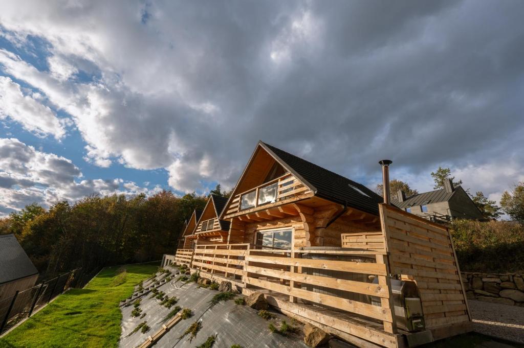 een houten hut met een zwart dak bij Domek drewniany w górach Jacuzzi & Balia - Osada Chełm in Stróża