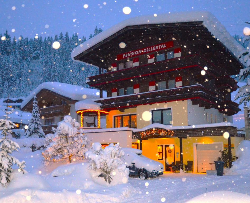 un edificio cubierto de nieve con un coche delante en Pension Zillertal en Gerlos