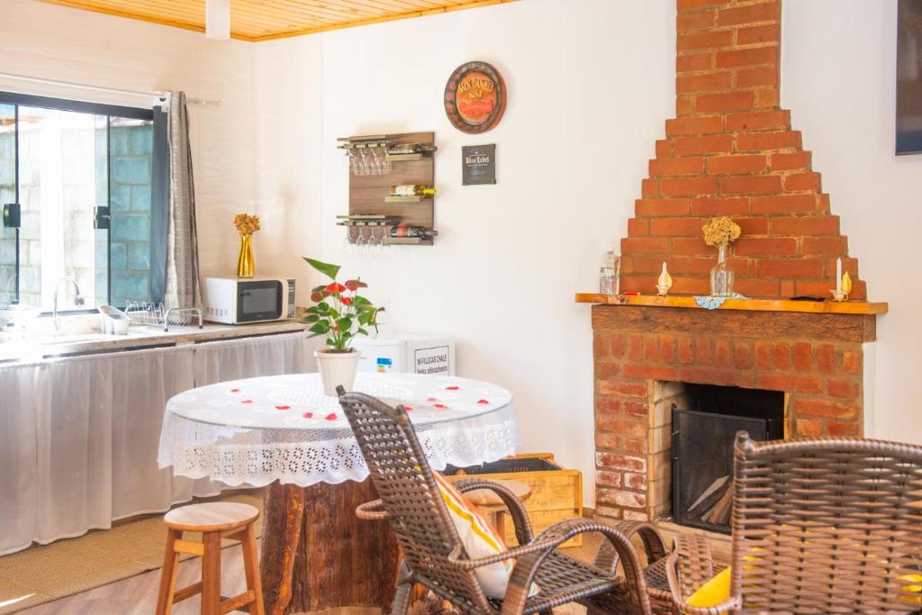 a living room with a table and a fireplace at Chalé Lírio Cachoeira do Vale in Monte Verde
