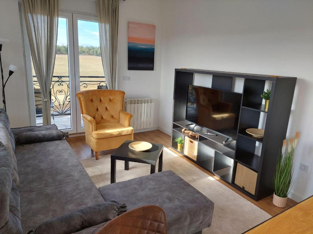 una sala de estar con un sofá y una silla en Moon Apartman Zlatibor, en Zlatibor