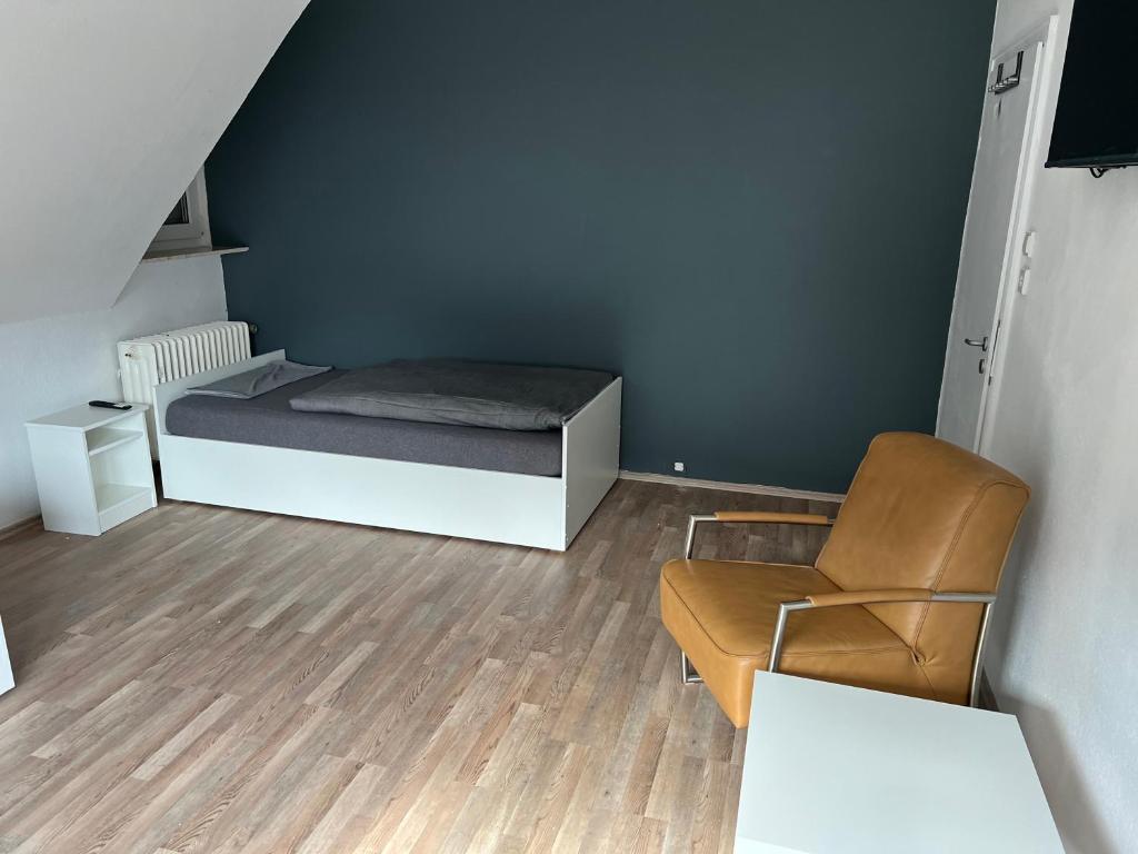een kleine kamer met een bed en een stoel bij Pension Gauerbach Lingen in Lingen
