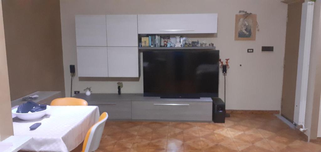 un soggiorno con tavolo e grande TV di Nonna Anna House a Napoli