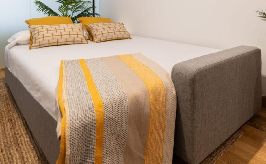 een groot bed met een deken erop bij Espectacular Apartamento Olívico con Parking in Vigo