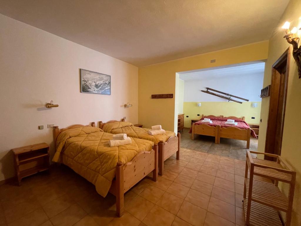 una camera con due letti e una porta di accesso ad una stanza di Hotel Genzianella a Santa Caterina Valfurva
