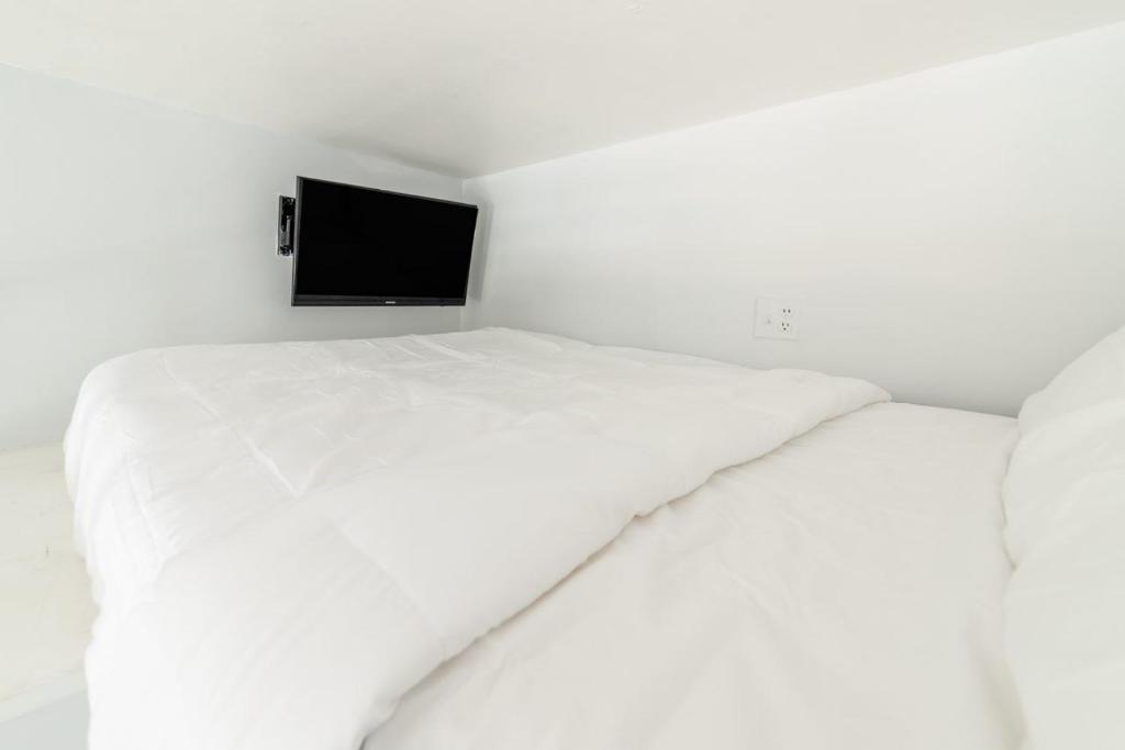 two white beds in a white room with a television at Apartment 1427: Fort Greene in Brooklyn