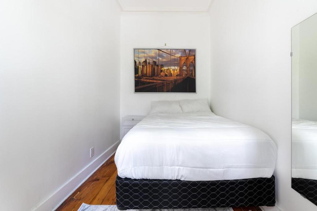 ブルックリンにあるApartment 1411: Fort Greeneの白いベッドと壁に絵画が飾られたベッドルーム1室