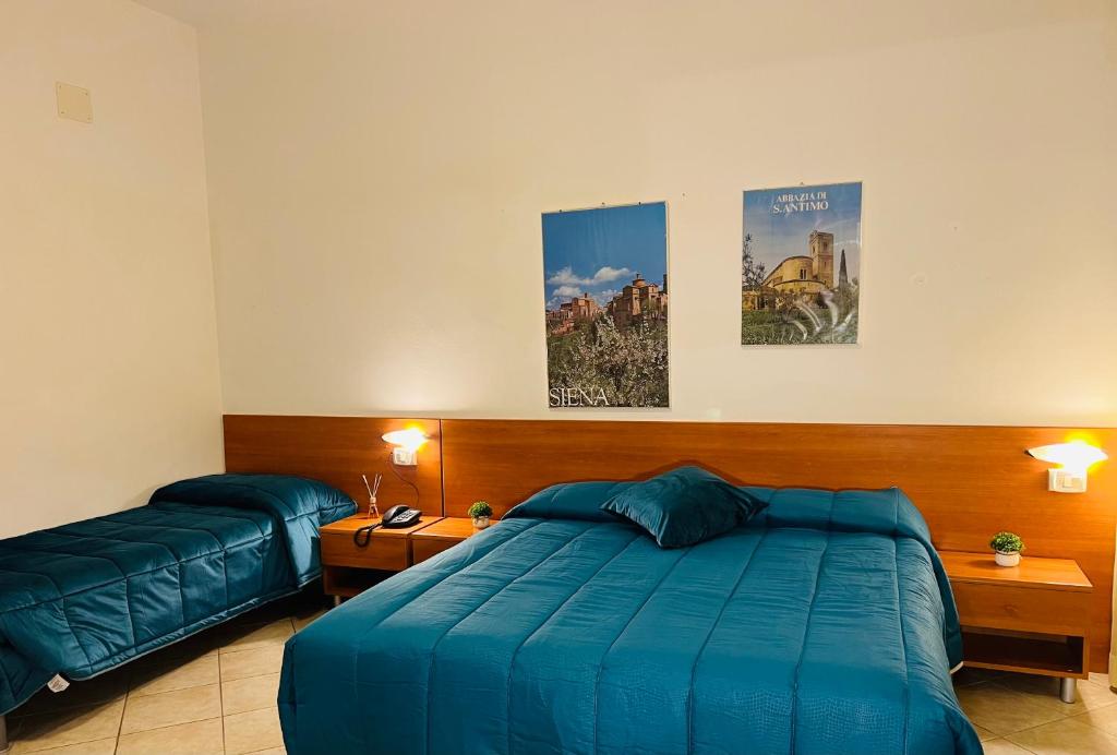 a bedroom with a large blue bed and two beds sidx sidx sidx at Hotel Vico Alto Siena in Siena