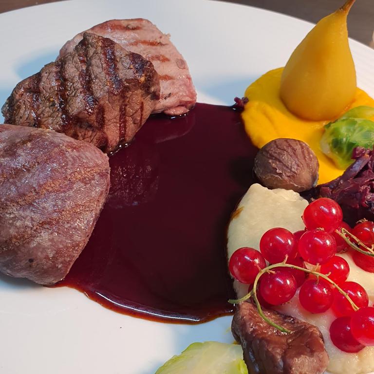 a plate of food with meat and fruit on it at Hôtel du Cygne in Bevaix
