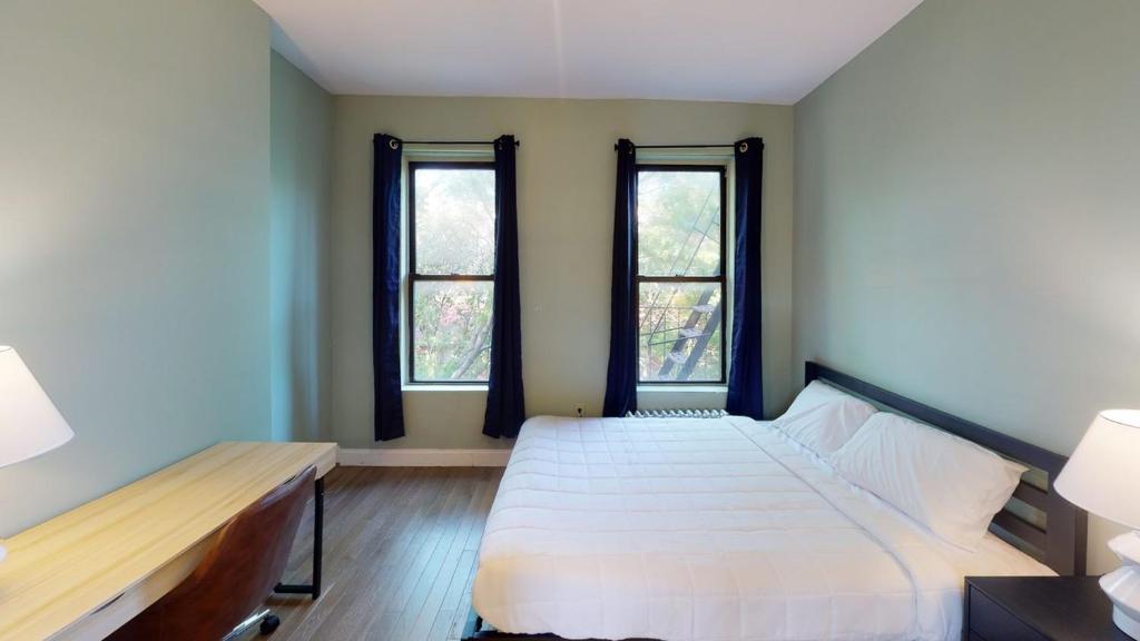 1 dormitorio con 2 camas y 2 ventanas en Apartment 566: East Village, en Nueva York