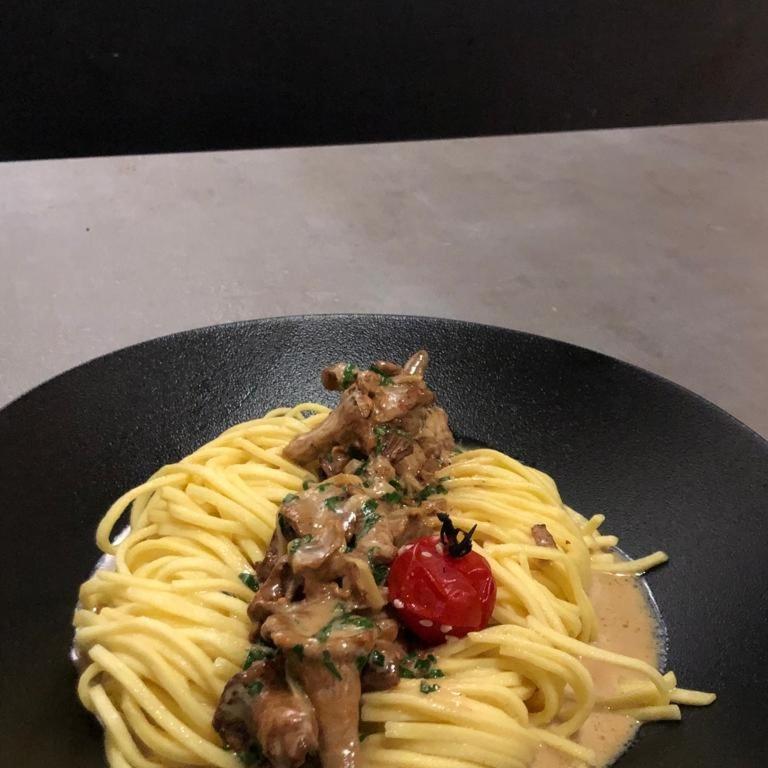 a plate of pasta with meat and a tomato at Hôtel du Cygne in Bevaix