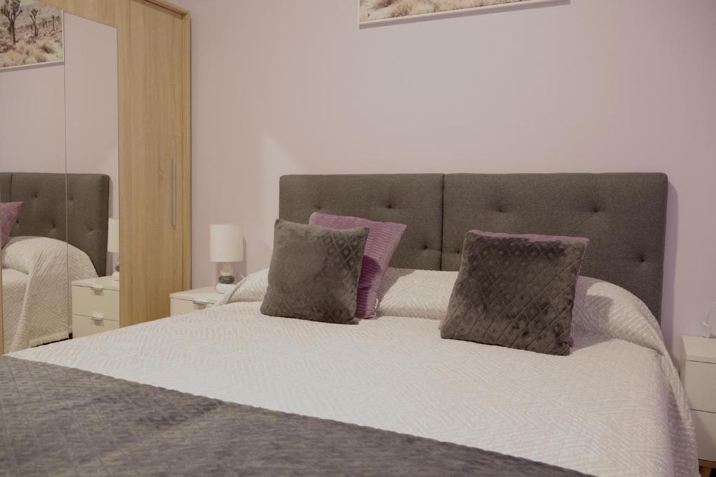 a bedroom with a bed with purple and gray pillows at Village Center One Bedroom Apartment in Porto Moniz