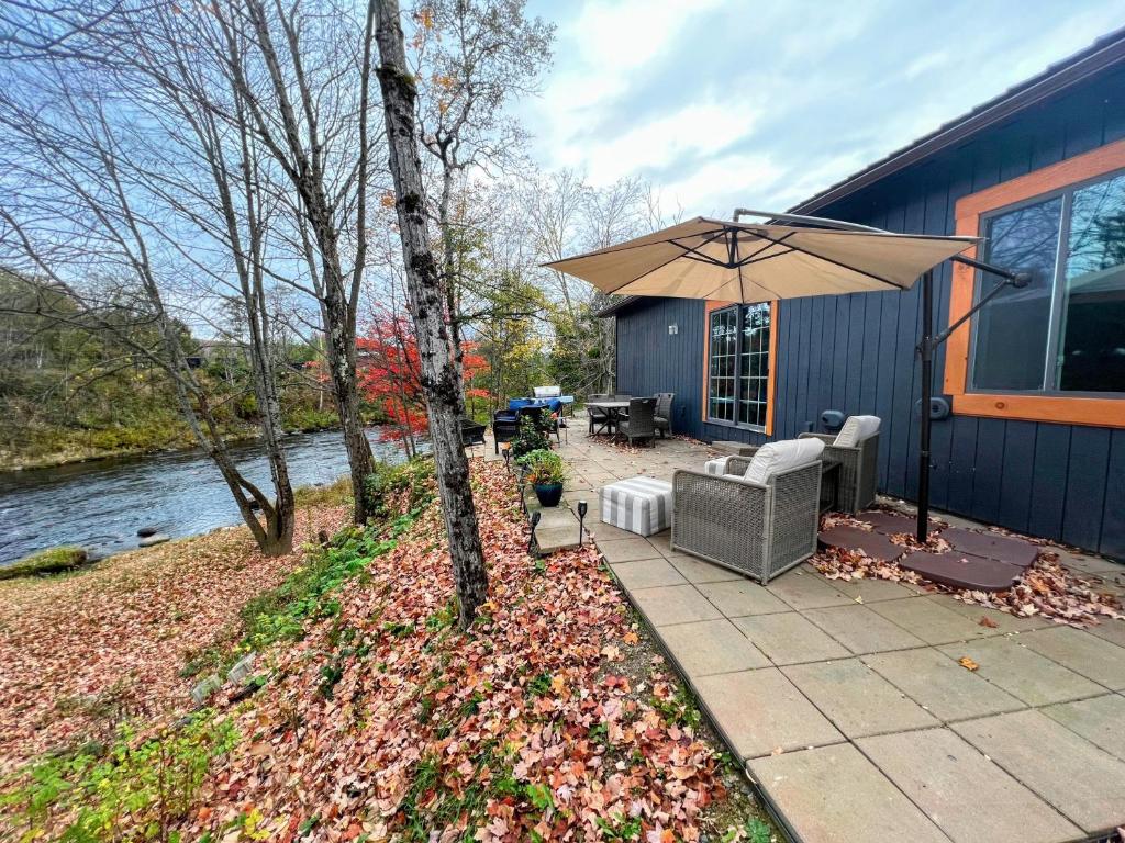 un patio con sombrilla junto a una casa en 37PA Superbly appointed riverfront home in LIttleton! Skiing, hiking, firepit, wifi! en Littleton