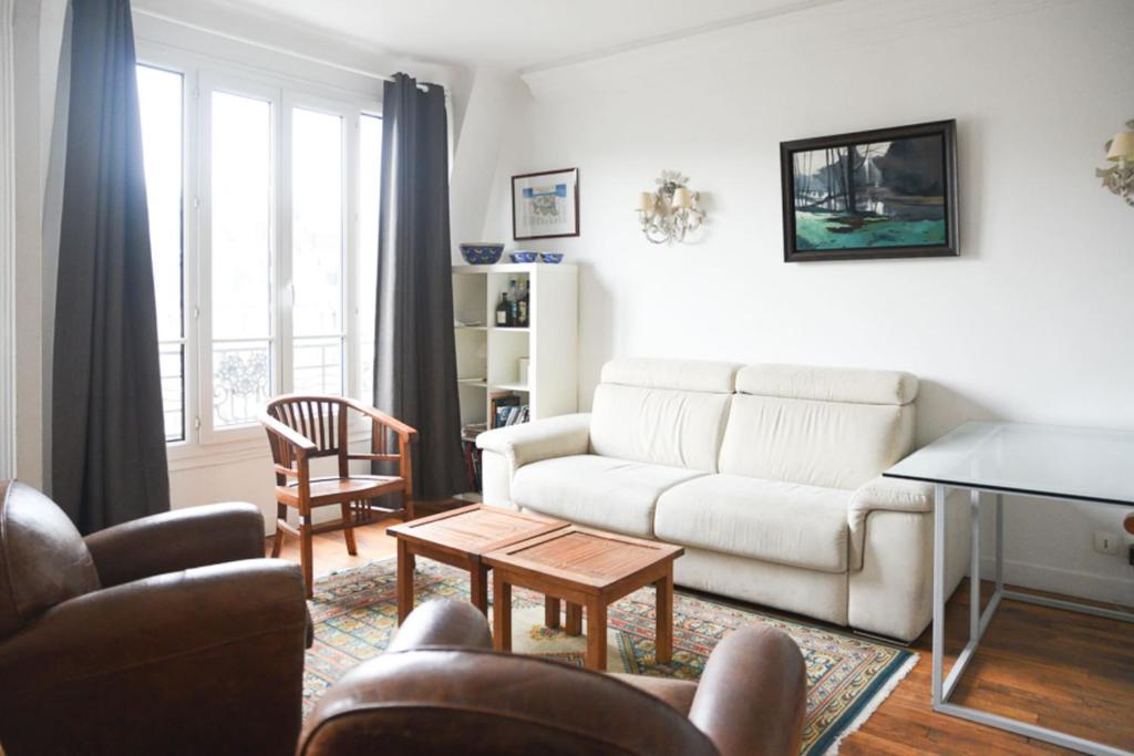 un soggiorno con divano e tavolo di Bright and spacious love cocoon in Paris 16th a Parigi