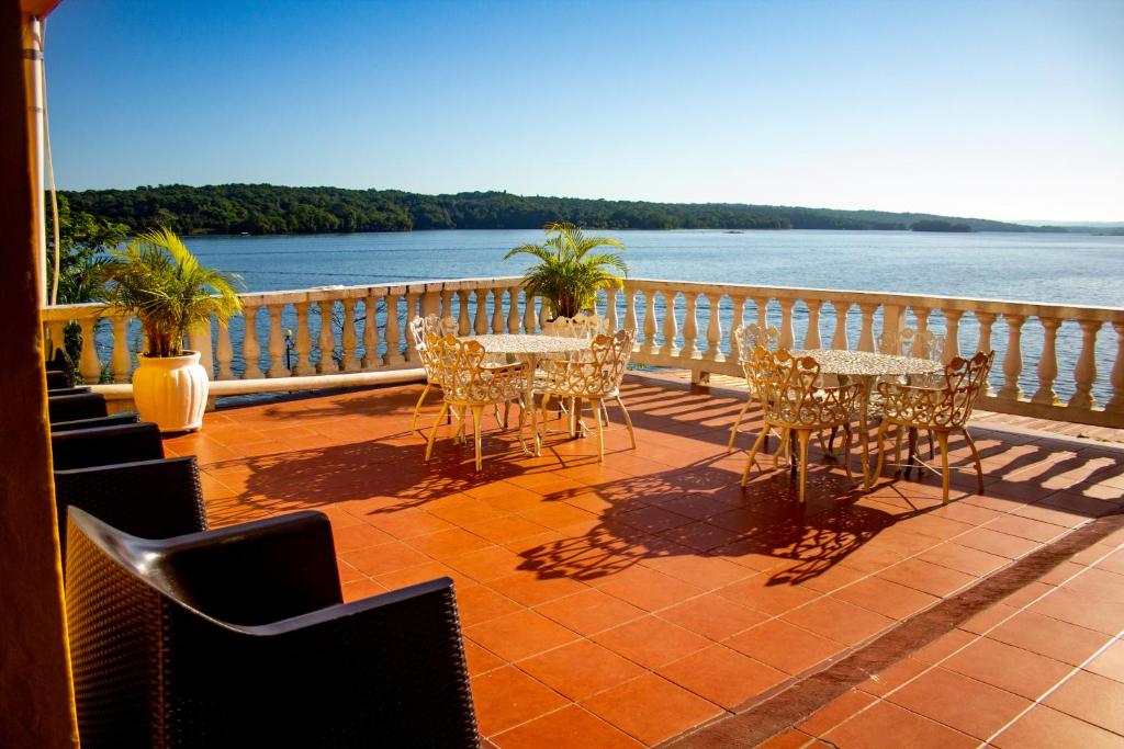 uma varanda com mesas e cadeiras e vista para a água em Hotel Villa del Lago em Flores